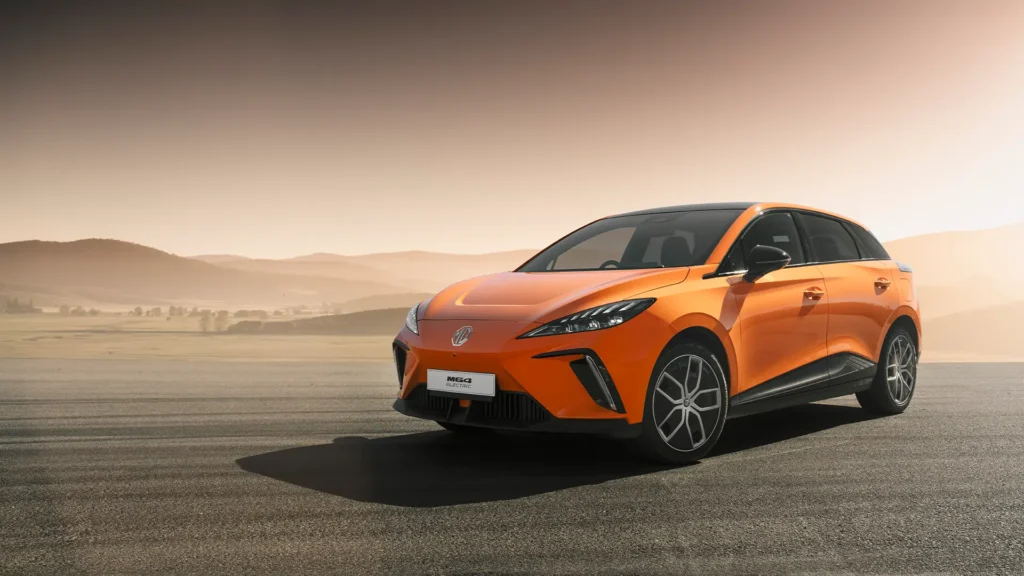 Oransje elbil parkert, åser og uklar himmel i bakgrunnen.