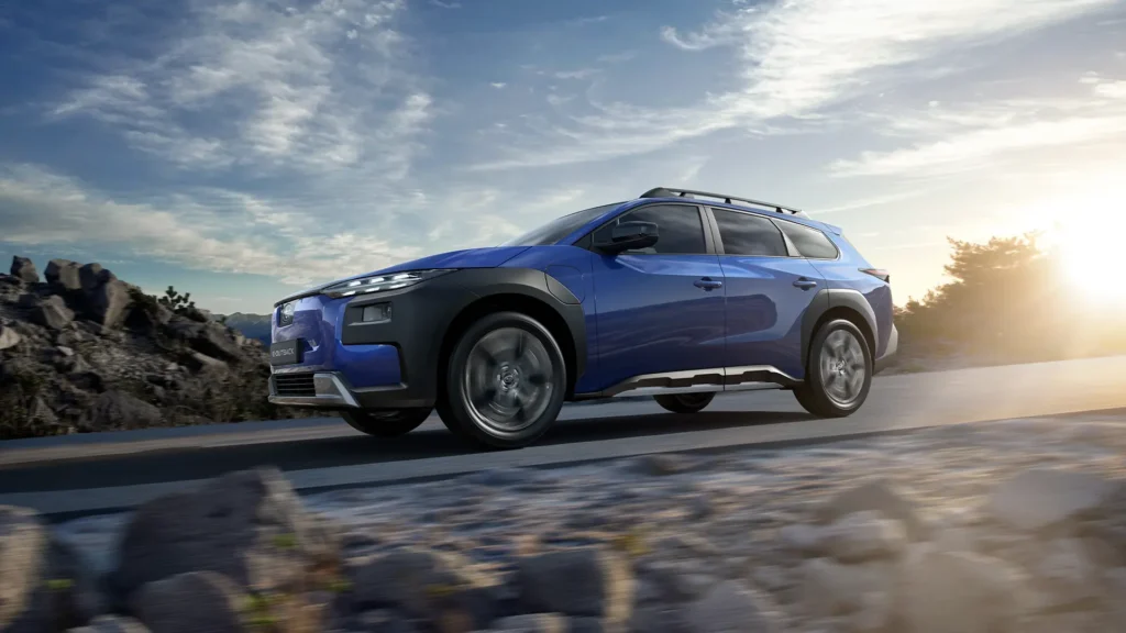 Blå SUV på fjellvei ved solnedgang, steiner foran.