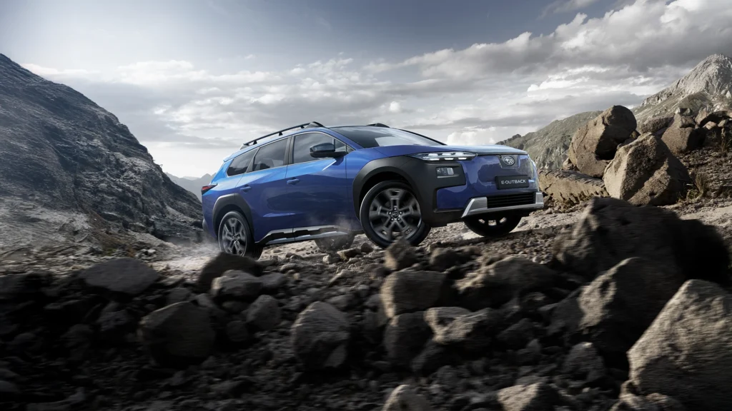 Blå SUV kjører på steinete terreng i fjellandskap.