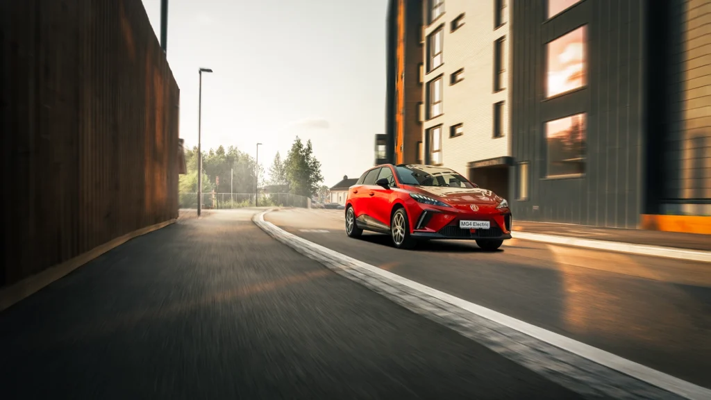 Rød elbil kjører alene i byen på dagtid.